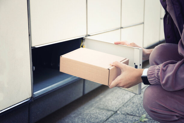 Kundin holt ein Paket im Hermes-Paketshop beziehungsweise an einer Paketstation ab